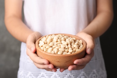 Woman holding bowl with shelled peanuts, closeup