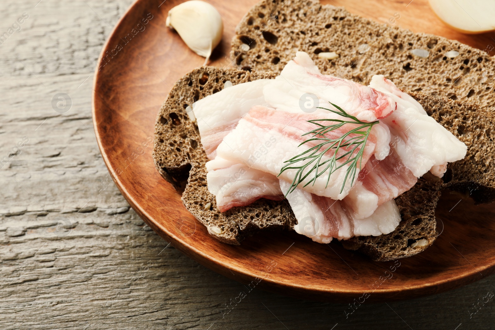 Photo of Tasty salt pork with rye bread and dill on wooden table, closeup