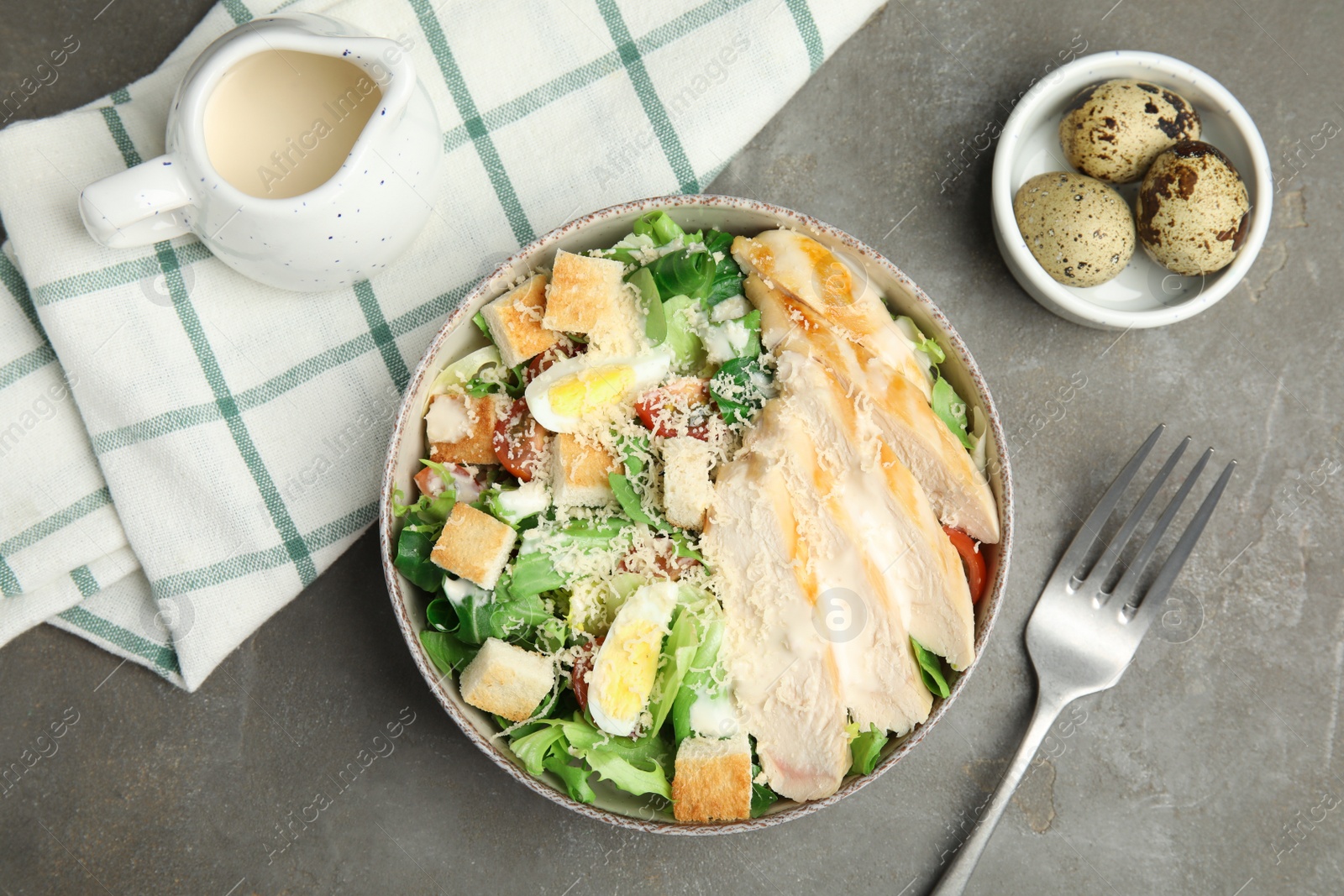 Photo of Delicious fresh Caesar salad in bowl on grey table, flat lay