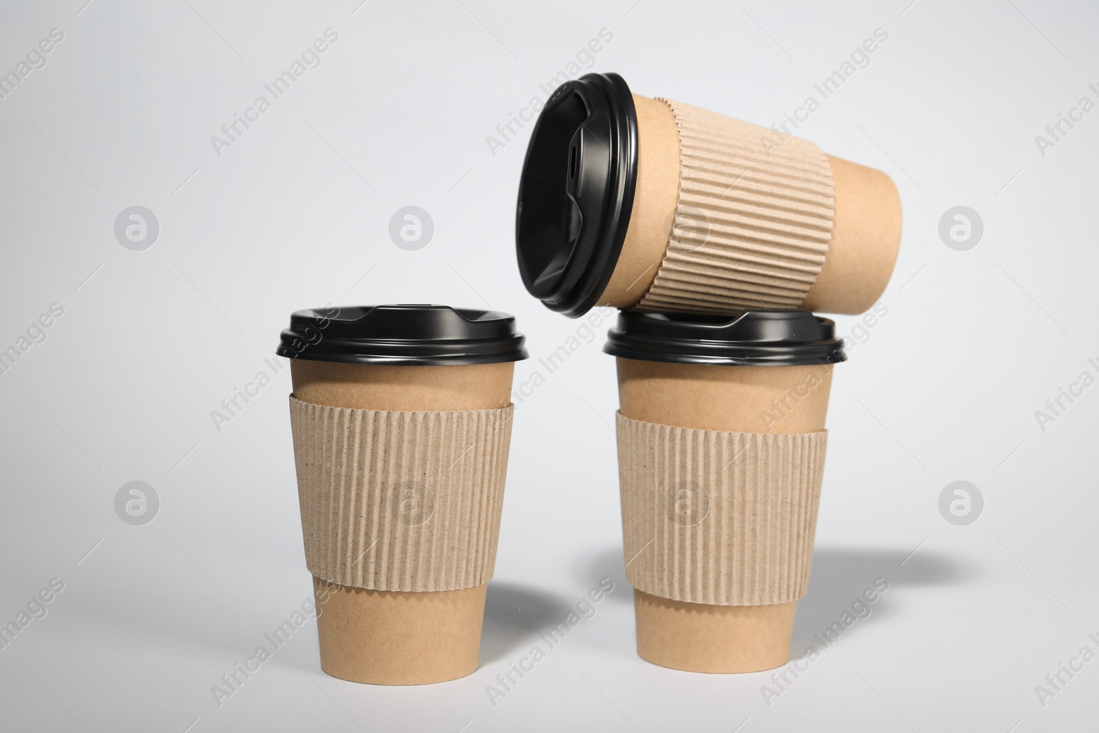 Photo of Paper cups with black lids on light gray background. Coffee to go