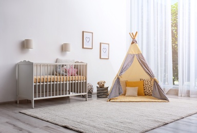 Photo of Cozy baby room interior with play tent and toys