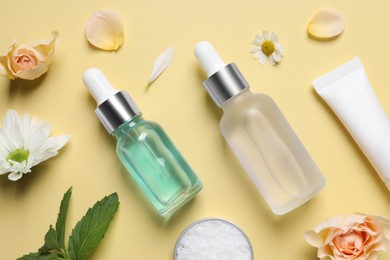 Photo of Flat lay composition with cosmetic serums on pale yellow background