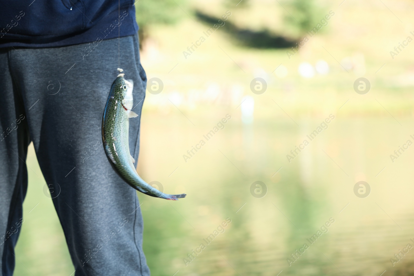Photo of Man with caught fish on blurred background. Space for text