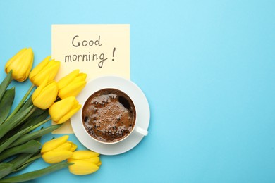 Photo of Cup of aromatic coffee, beautiful yellow tulips and Good Morning note on light blue background, flat lay. Space for text