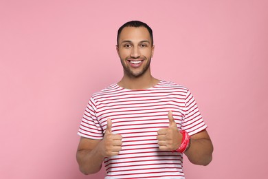 Photo of Happy African American man showing thumbs up on pink background