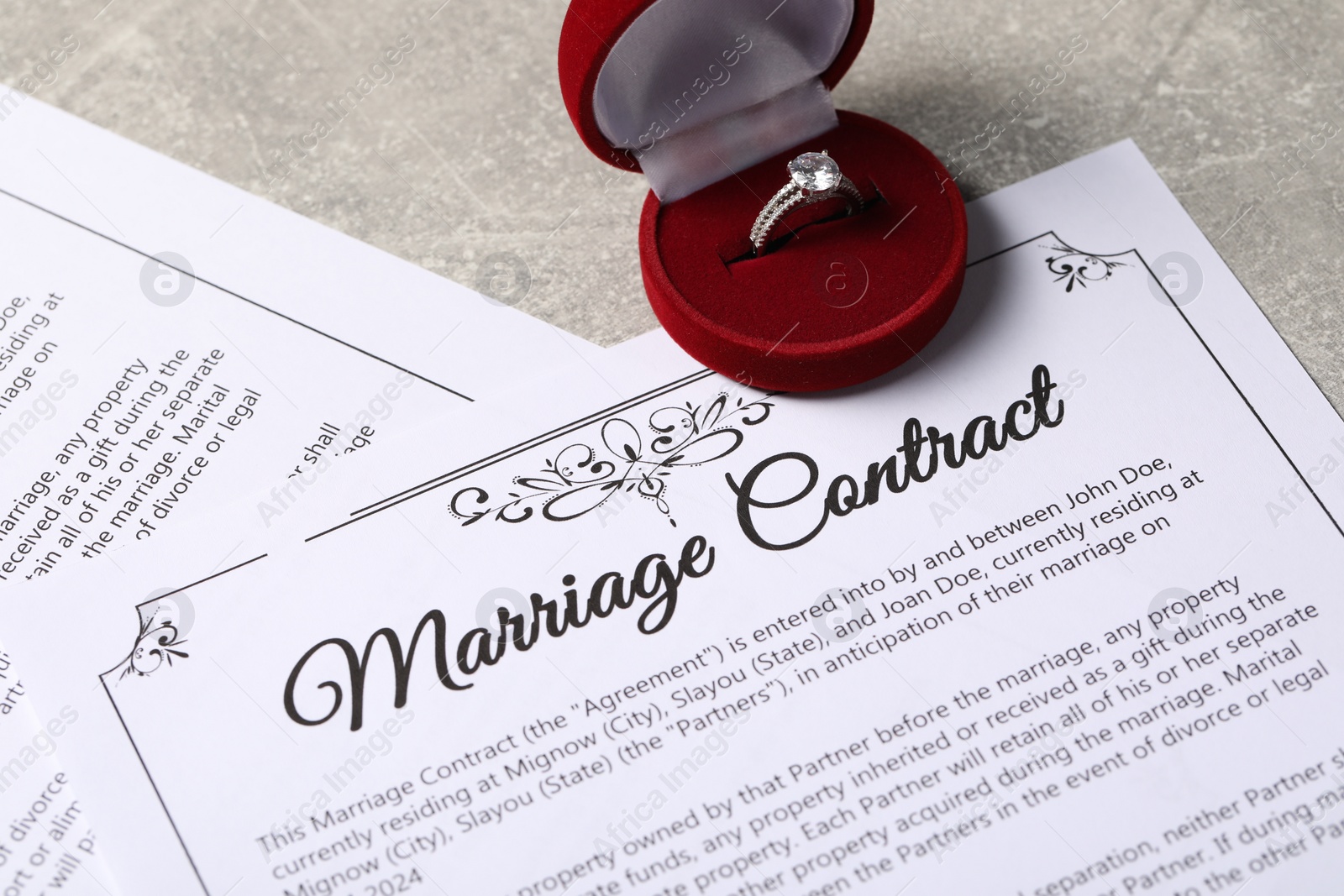 Photo of Marriage contract and ring with gemstone on grey table