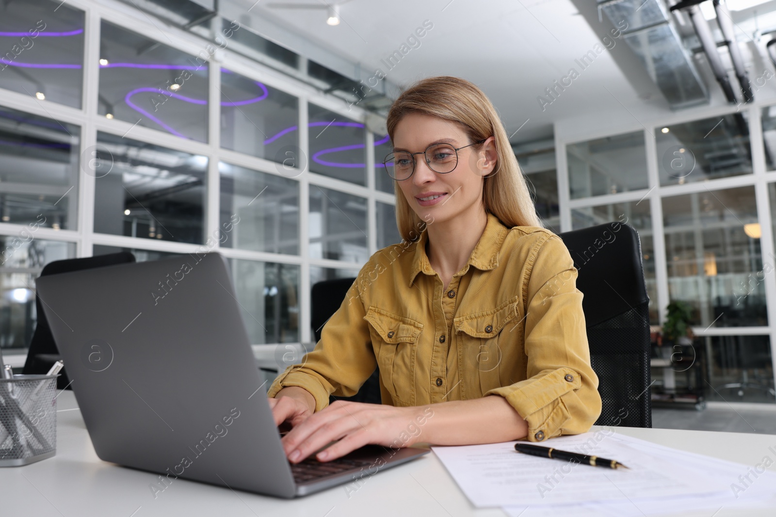 Photo of Woman working on laptop at white desk in office