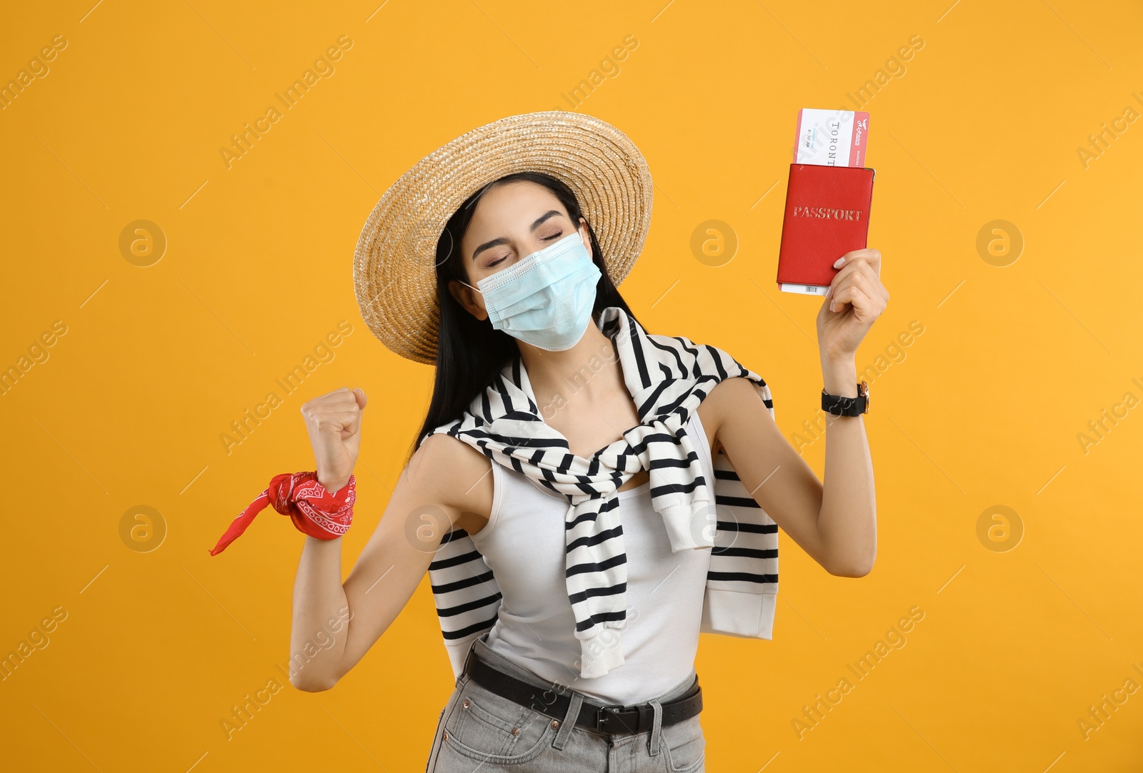 Photo of Female tourist in medical mask with ticket and passport on yellow background. Travelling during coronavirus pandemic