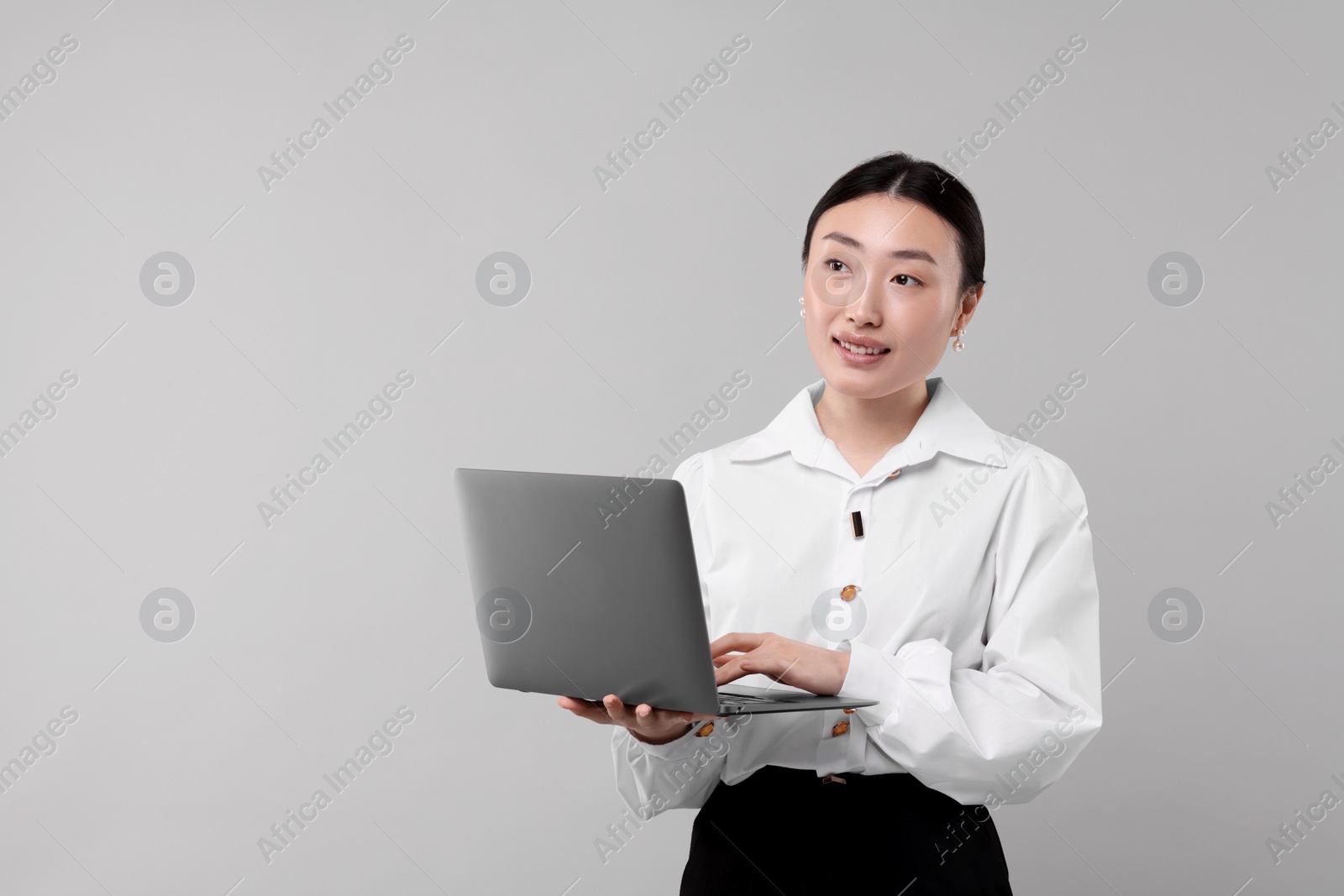 Photo of Portrait of smiling businesswoman with laptop on grey background. Space for text