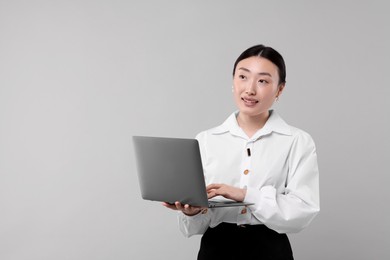 Photo of Portrait of smiling businesswoman with laptop on grey background. Space for text