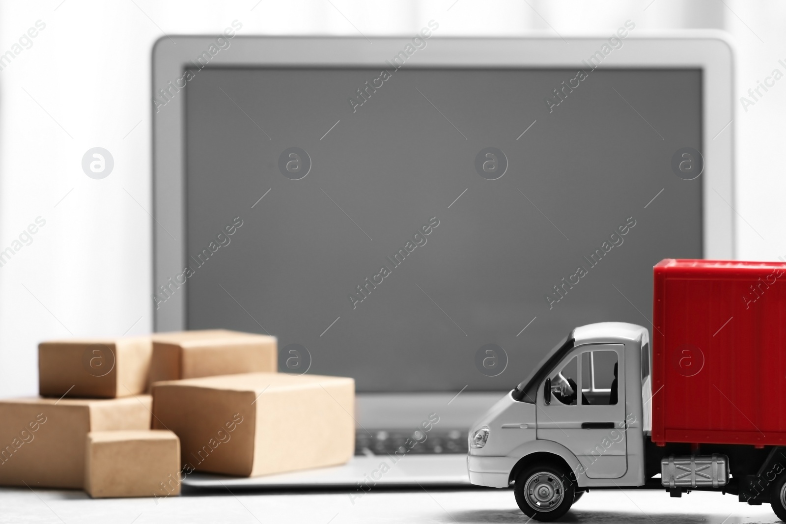 Photo of Toy truck near laptop on table. Logistics and wholesale concept