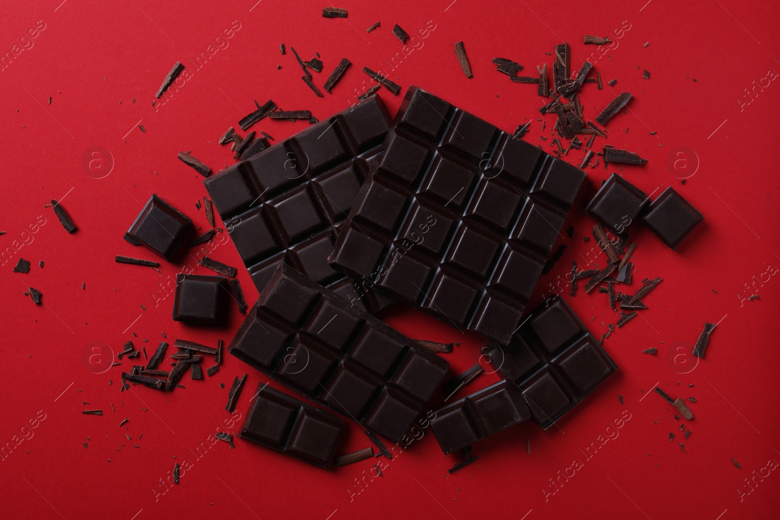 Photo of Tasty dark chocolate on red background, flat lay