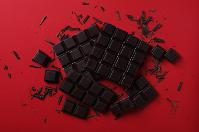 Photo of Tasty dark chocolate on red background, flat lay