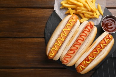 Photo of Delicious hot dogs with sauces on wooden table, top view. Space for text