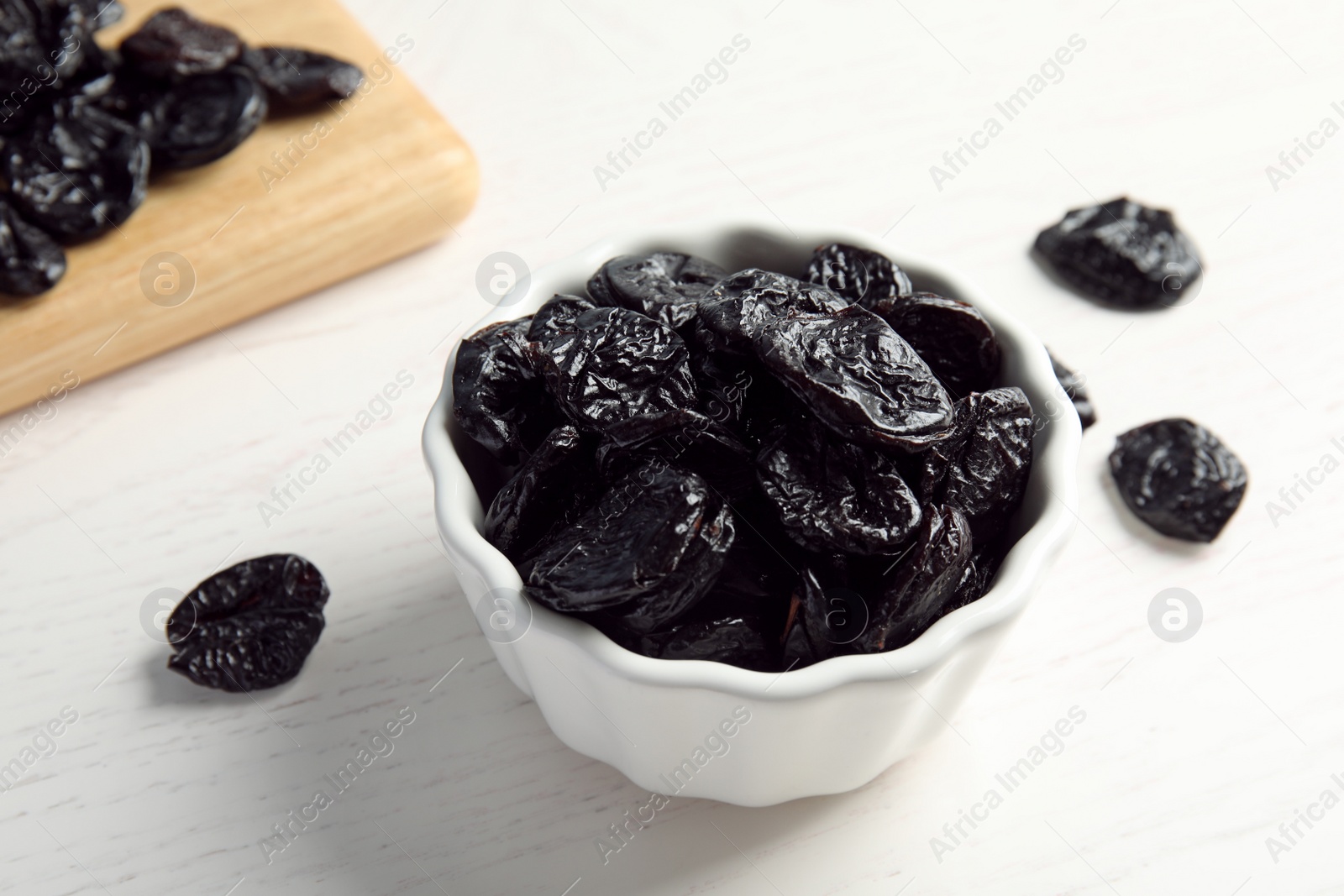 Photo of Bowl of sweet dried plums on table. Healthy fruit