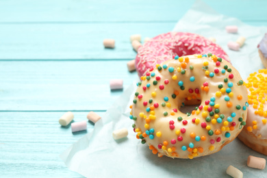 Delicious glazed donuts on blue wooden table, closeup. Space for text