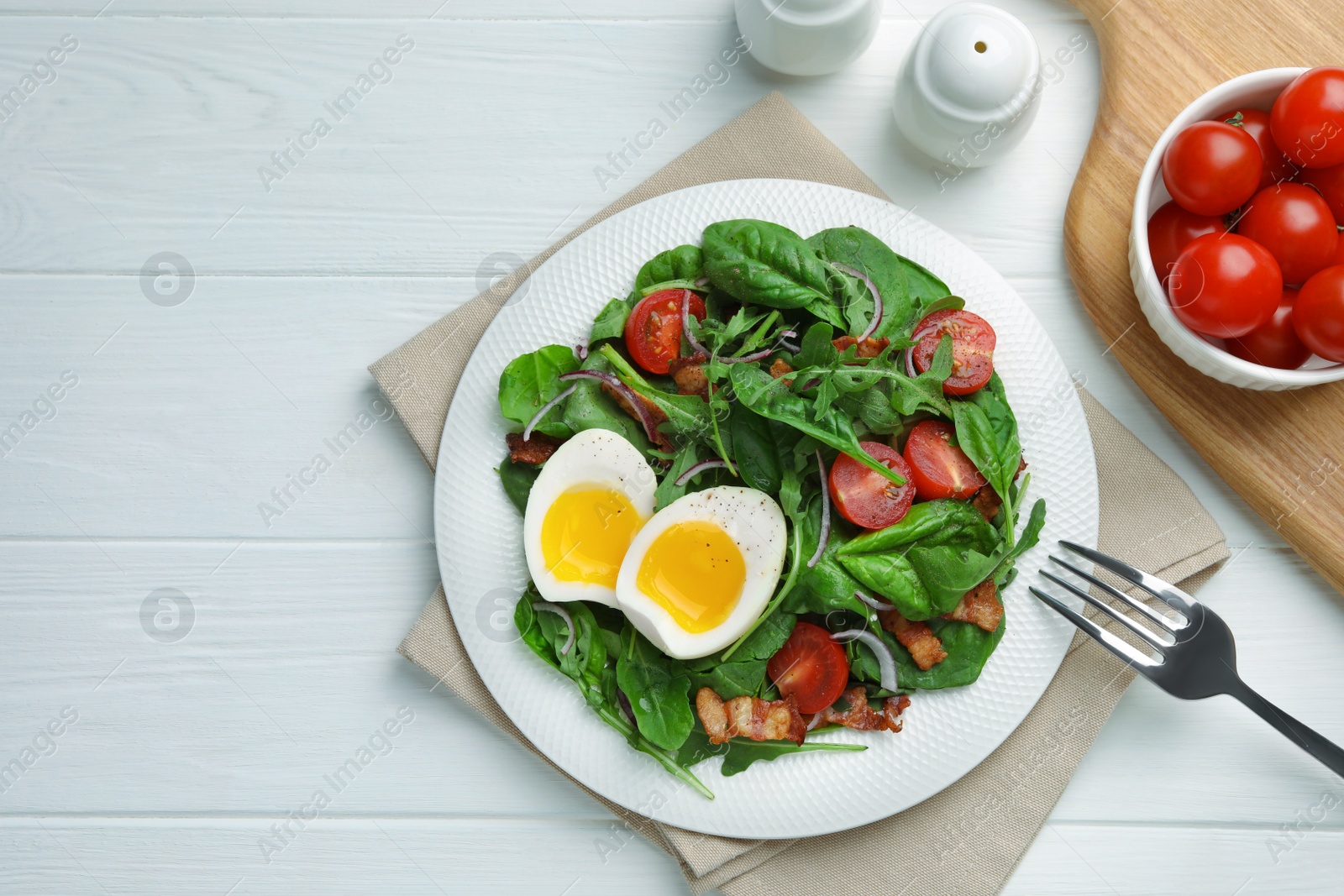 Photo of Delicious salad with boiled egg, bacon and tomatoes served on white wooden table, flat lay