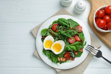 Delicious salad with boiled egg, bacon and tomatoes served on white wooden table, flat lay