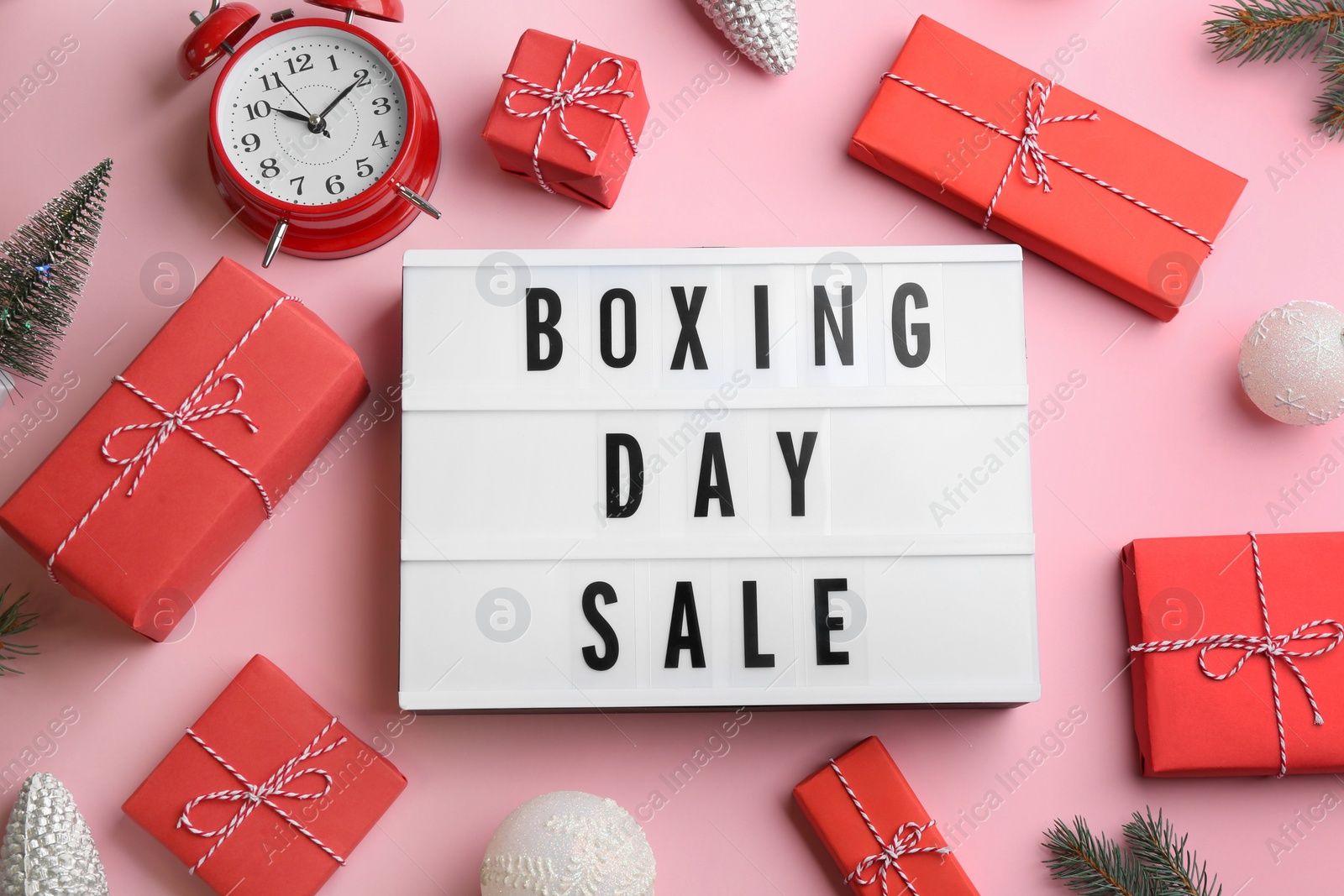 Photo of Lightbox with phrase BOXING DAY SALE and Christmas decorations on light pink background, flat lay