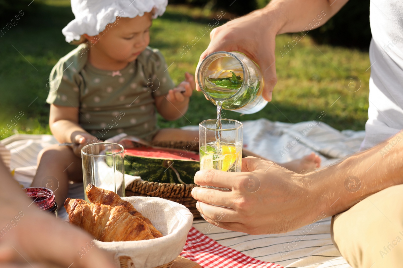 Photo of Family with cute child having picnic on sunny day in garden, closeup