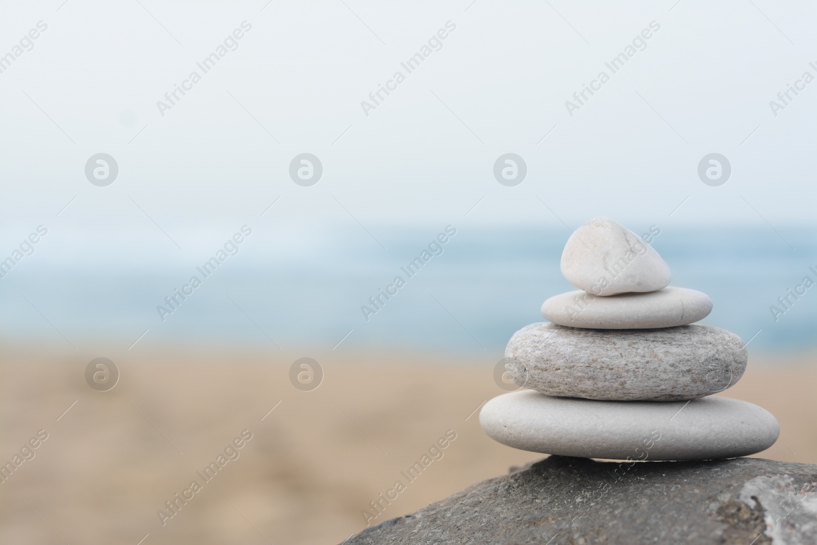 Photo of Stack of stones on rock near sea, space for text