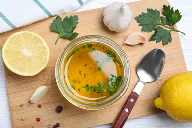 Jar with lemon sauce and ingredients on white wooden table, flat lay. Delicious salad dressing