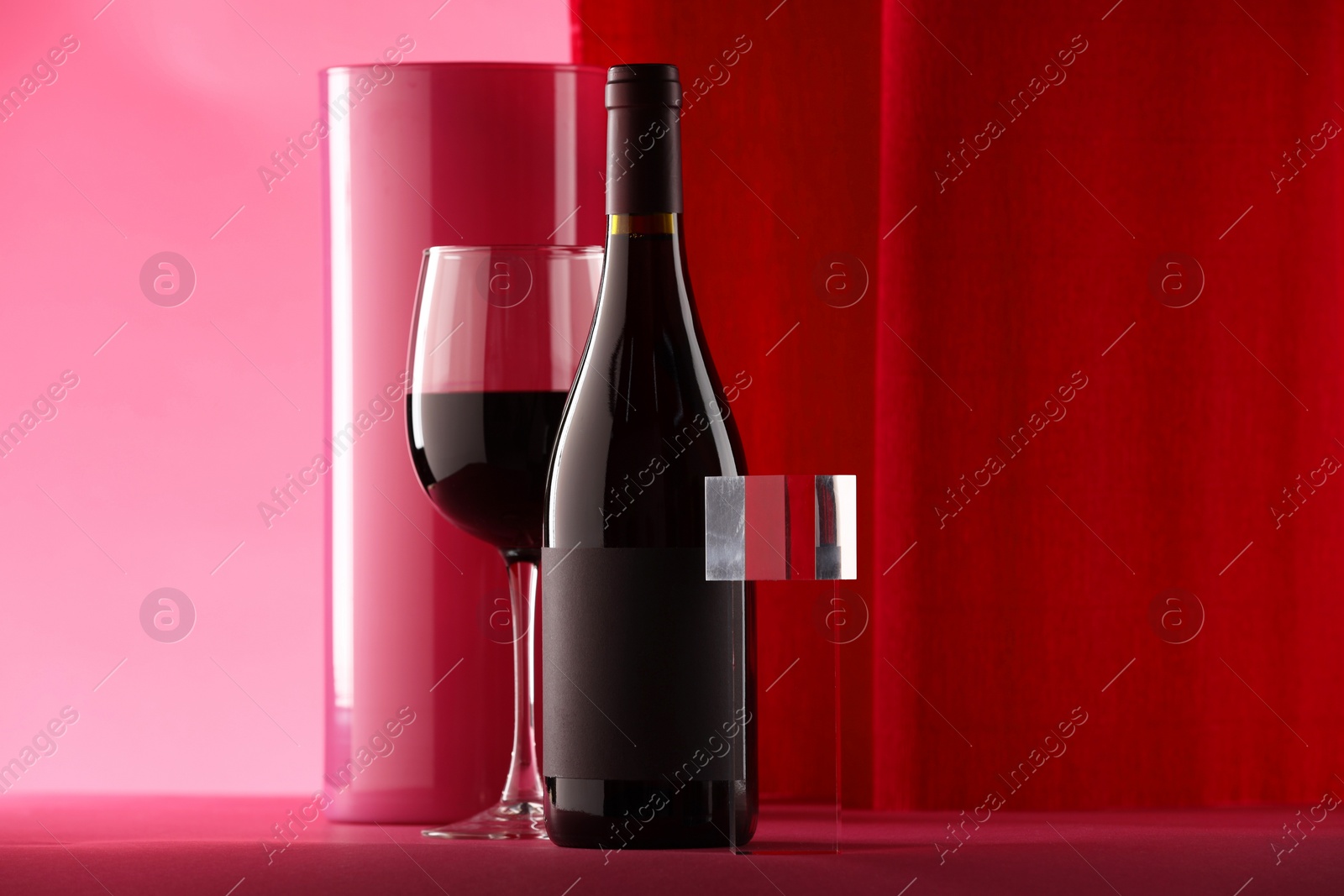 Photo of Stylish presentation of delicious red wine in bottle and glass on color background. Space for text