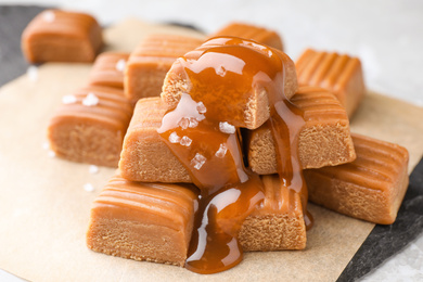Photo of Delicious salted caramel on parchment, closeup view
