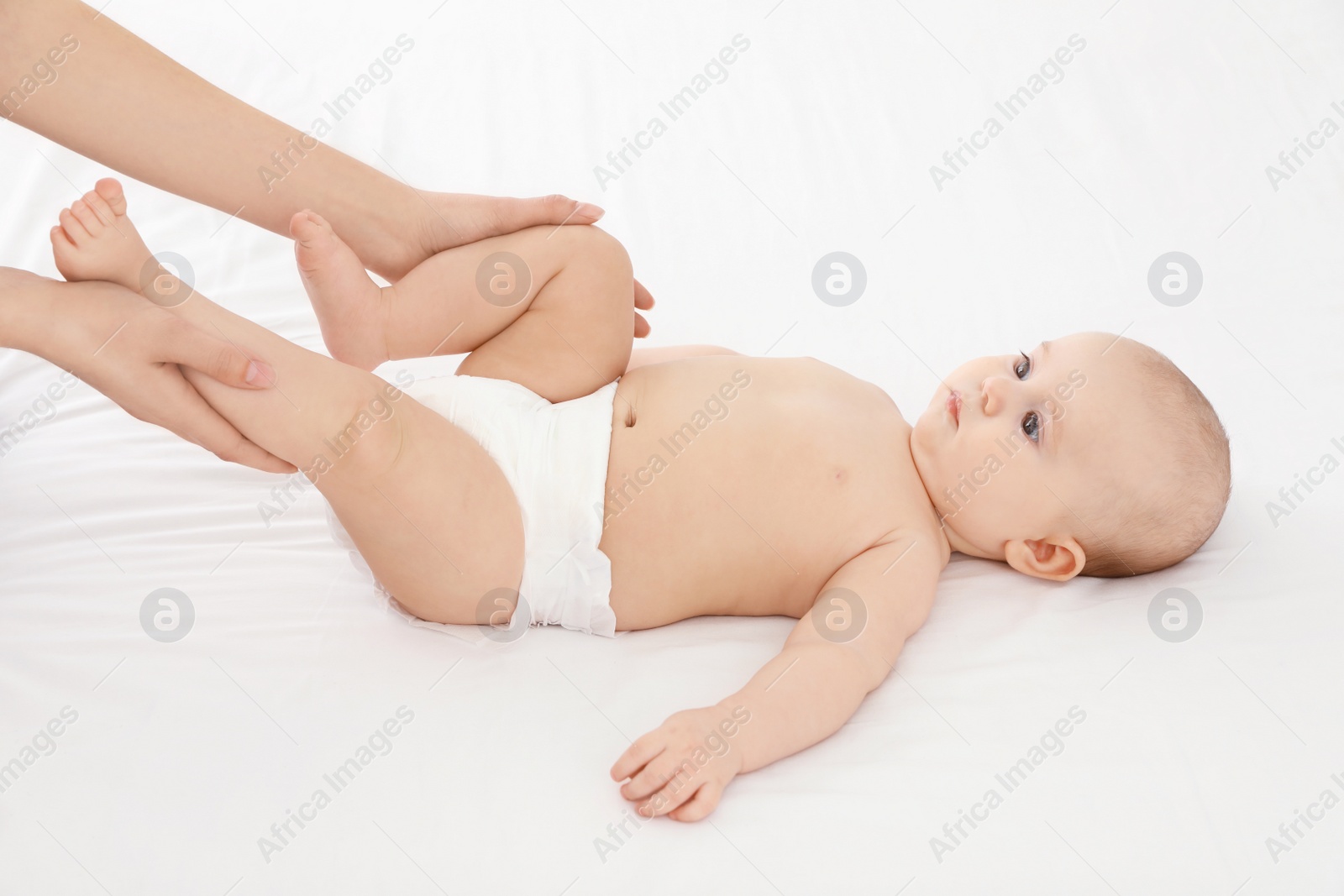 Photo of Mother and her cute child on white bed. Baby massage and exercises