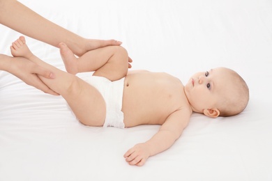 Mother and her cute child on white bed. Baby massage and exercises