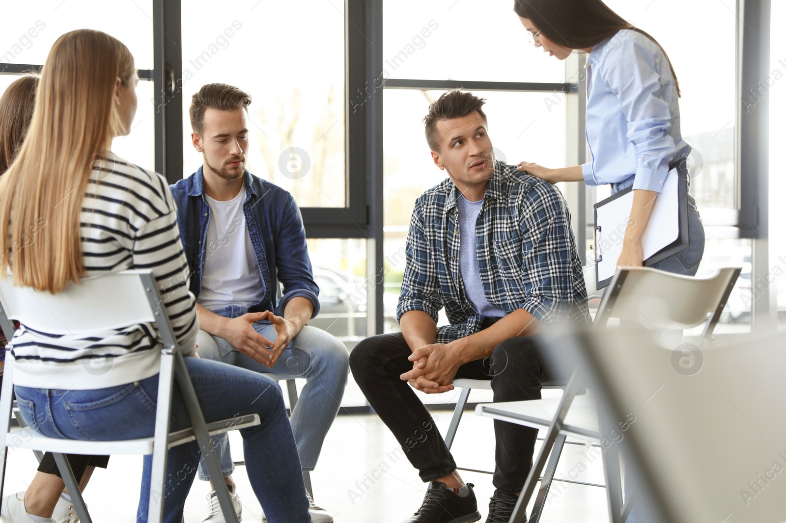 Photo of Psychotherapist working with patients in group therapy session indoors