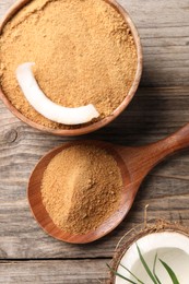 Photo of Coconut sugar in bowl, spoon and fruit on wooden table, flat lay