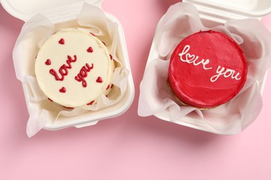 Photo of Bento cakes in takeaway boxes on pink table, flat lay. St. Valentine's day surprise