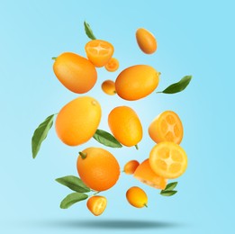 Image of Delicious fresh kumquats and green leaves falling on turquoise background