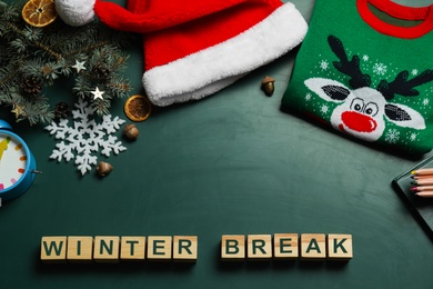 Photo of Wooden cubes with text Winter Break and Christmas decor on green background, flat lay. School holidays