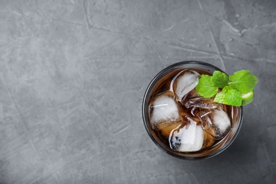 Glass of Rum and Cola cocktail on grey stone table, top view. Space for text