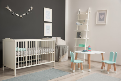 Photo of Cute baby room interior with modern crib near dark wall