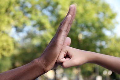 Photo of African American man stopping woman's fist outdoors, closeup. Antiracism concept