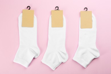 Photo of White cotton socks on light pink background, flat lay