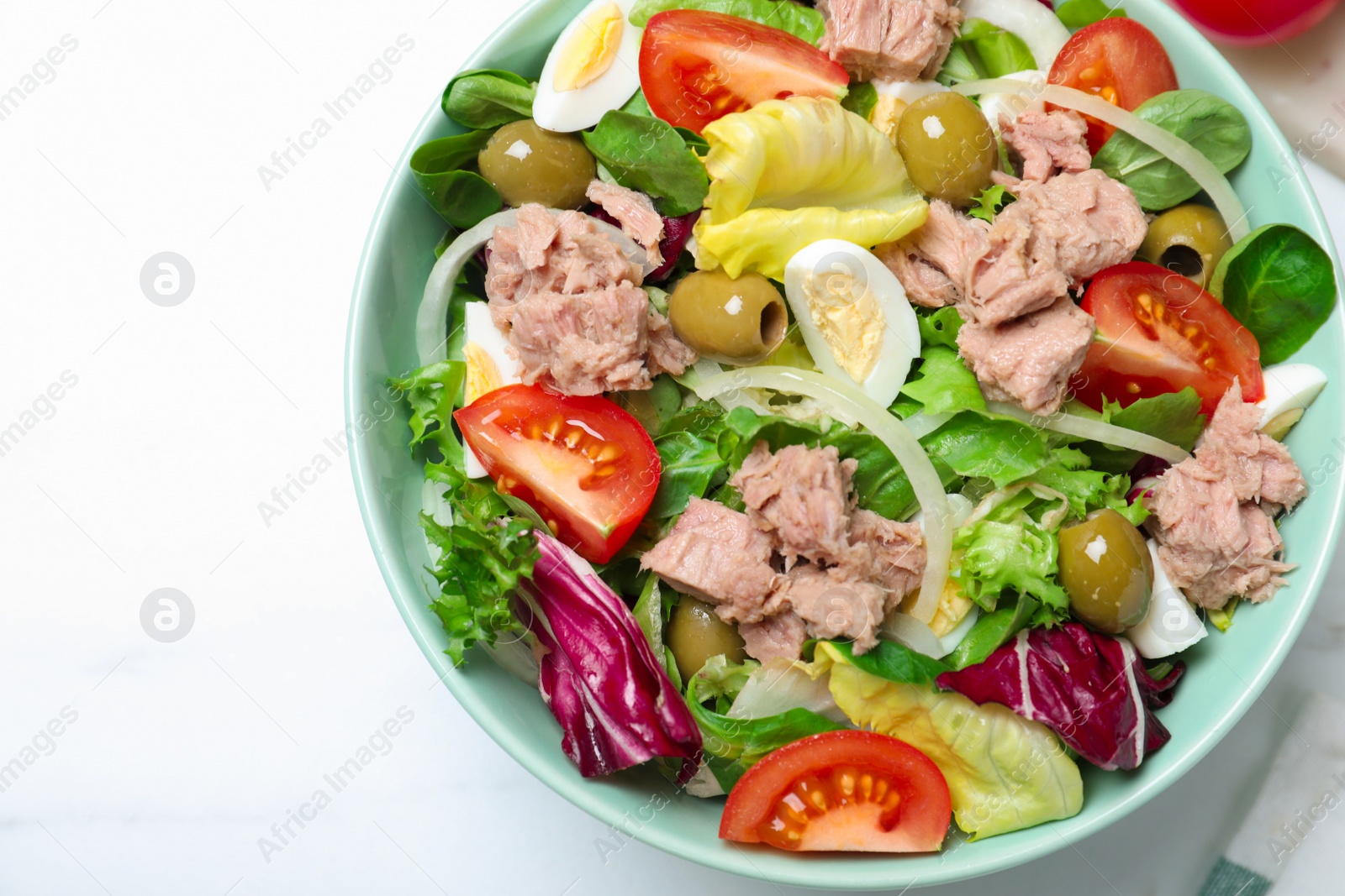 Photo of Bowl of delicious salad with canned tuna and vegetables on white table, top view