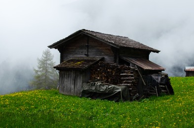 Photo of View of old wooden house on green hill