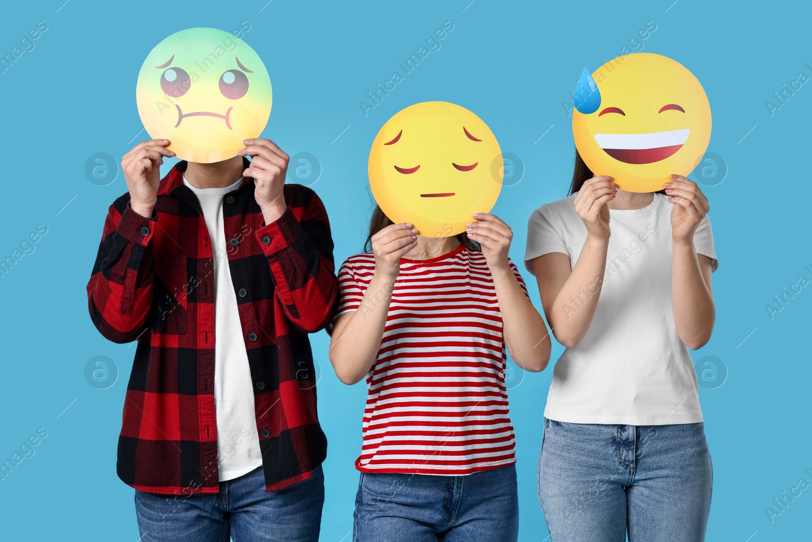 Photo of People covering faces with emoticons on light blue background