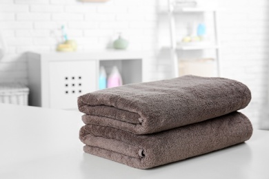 Photo of Stack of fresh towels on table in bathroom. Space for text