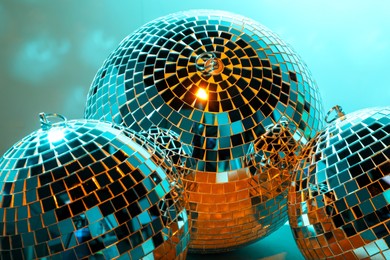 Photo of Shiny disco balls on turquoise background, closeup