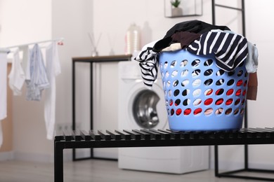 Photo of Laundry basket with clothes on black bench in bathroom. Space for text