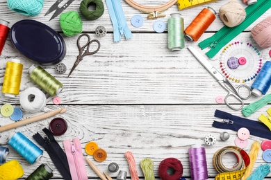 Photo of Composition with color threads and sewing accessories on wooden background, top view