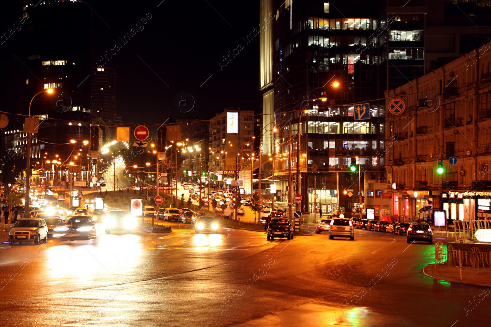 Photo of KYIV, UKRAINE - MAY 22, 2019: View of illuminated city street with road traffic and buildings