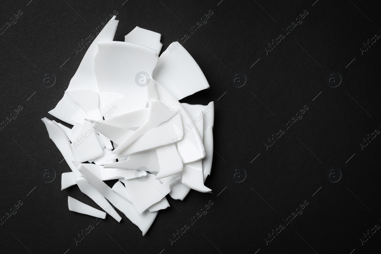 Photo of Divorce concept. Pieces of broken plate on black background, flat lay with space for text