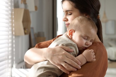 Photo of Happy young mother with her sleeping baby at home