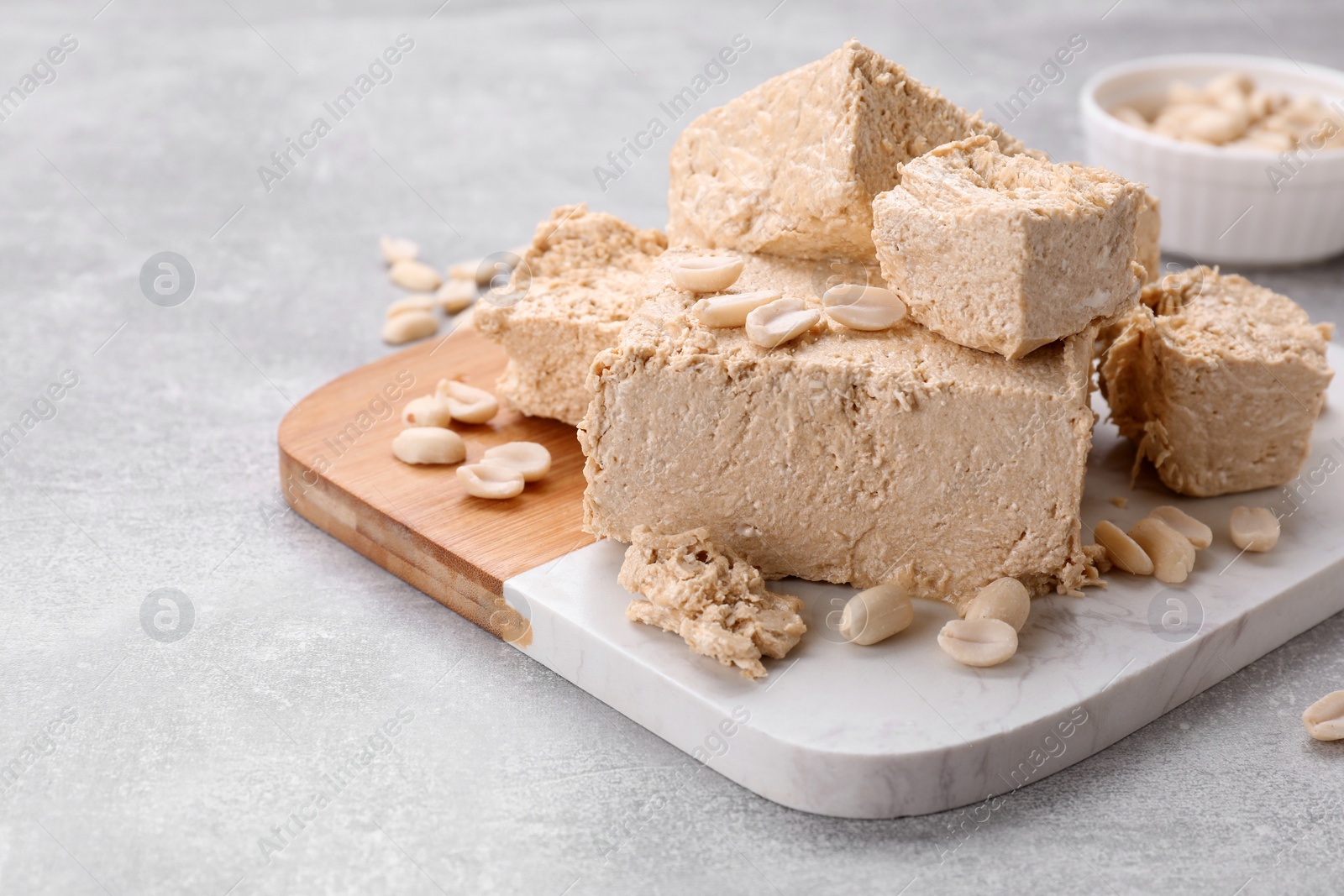 Photo of Pieces of tasty halva on light gray table, closeup. Space for text